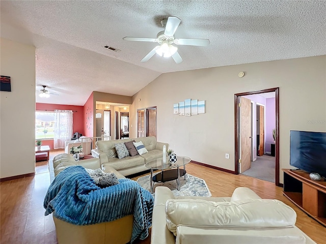 living room with a textured ceiling, vaulted ceiling, light hardwood / wood-style floors, and ceiling fan