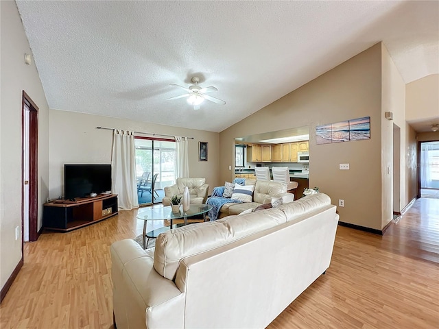 living room with ceiling fan, light hardwood / wood-style floors, vaulted ceiling, and a textured ceiling