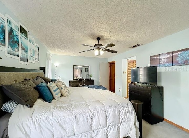 carpeted bedroom featuring ceiling fan and a textured ceiling