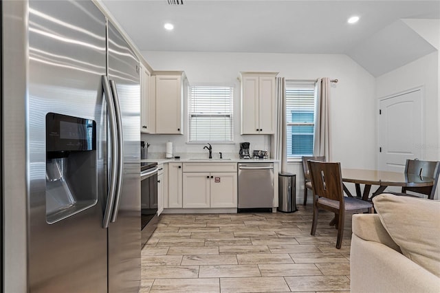 kitchen featuring white cabinetry, sink, vaulted ceiling, and stainless steel appliances