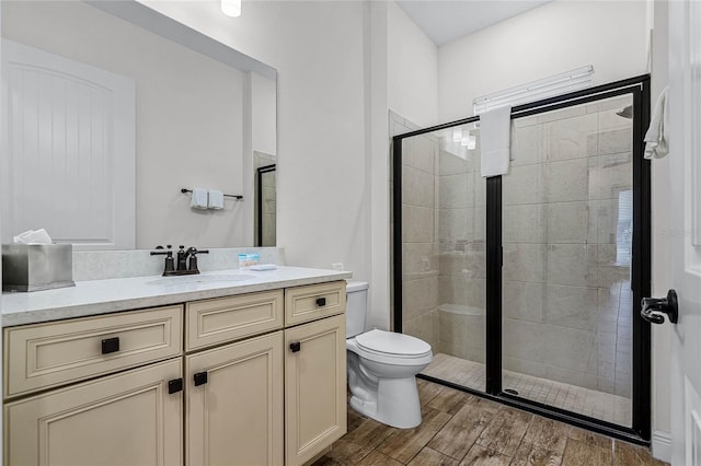 bathroom with a shower with door, vanity, and toilet