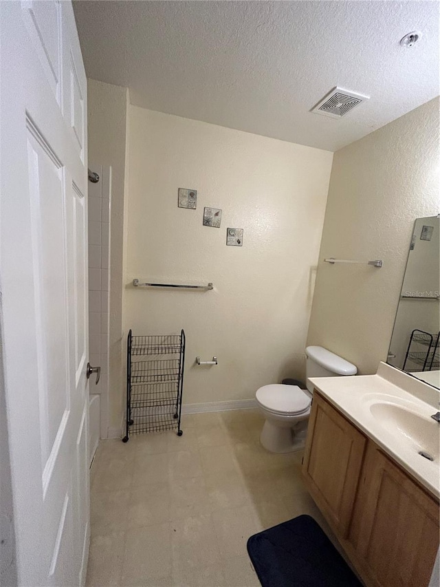 bathroom with vanity, a textured ceiling, and toilet