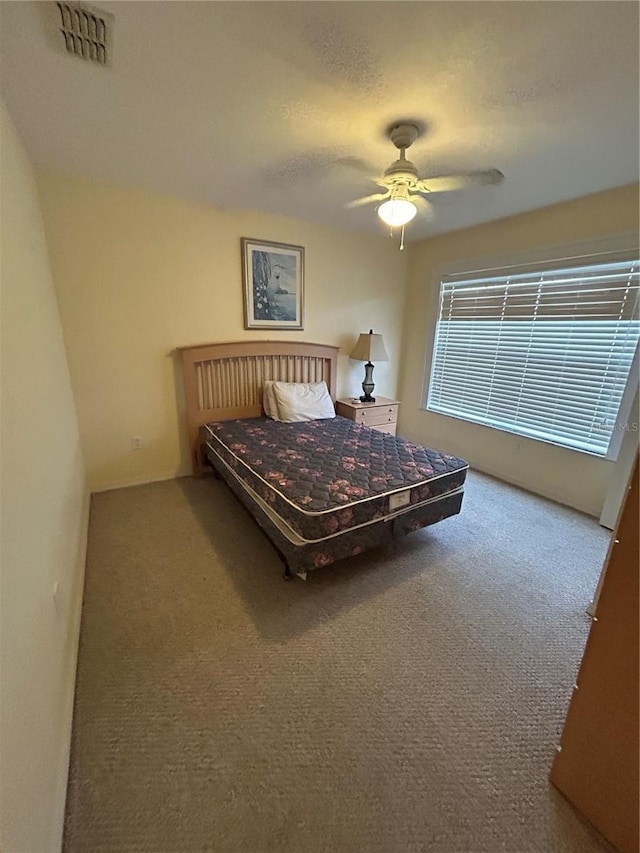 bedroom with ceiling fan, carpet floors, and a textured ceiling