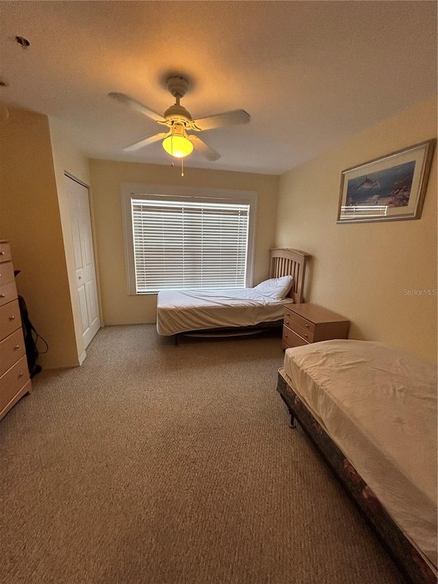 carpeted bedroom with ceiling fan and a closet