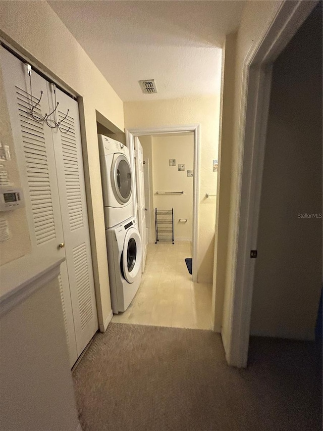 washroom featuring stacked washer and dryer and light colored carpet