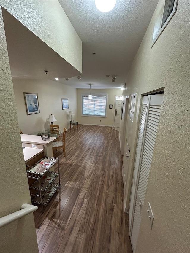 corridor with hardwood / wood-style floors and a textured ceiling