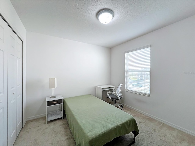 bedroom with light colored carpet, a closet, and a textured ceiling