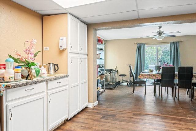 dining space featuring a drop ceiling, dark wood-type flooring, and ceiling fan