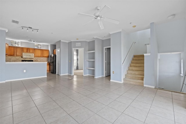 unfurnished living room featuring built in shelves, ornamental molding, ceiling fan, and light tile patterned flooring