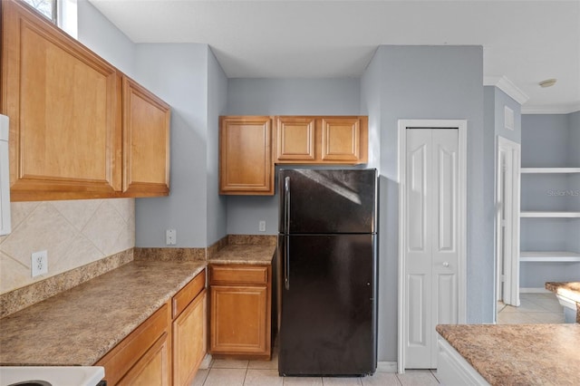 kitchen with decorative backsplash, light tile patterned flooring, and black fridge