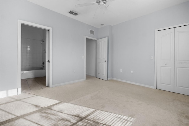 unfurnished bedroom with ceiling fan, ensuite bath, a closet, and light carpet