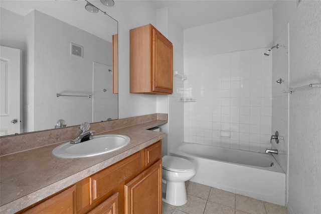 full bathroom featuring tile patterned flooring, vanity, tiled shower / bath, and toilet