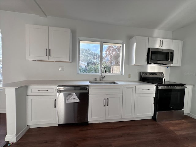 kitchen featuring appliances with stainless steel finishes, dark wood finished floors, white cabinetry, and a sink