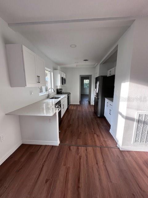 kitchen with white cabinetry, visible vents, dark wood finished floors, and a sink