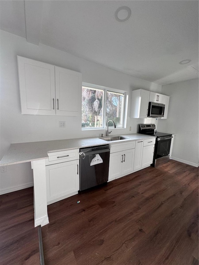 kitchen featuring dark wood finished floors, white cabinetry, stainless steel appliances, and a sink