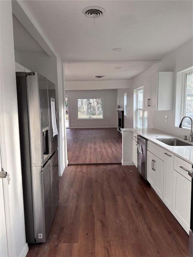 kitchen featuring visible vents, appliances with stainless steel finishes, white cabinets, a sink, and plenty of natural light