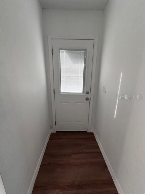 entryway with dark wood-type flooring and baseboards