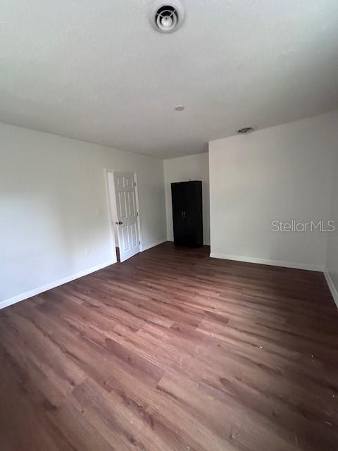 spare room featuring visible vents, baseboards, and wood finished floors