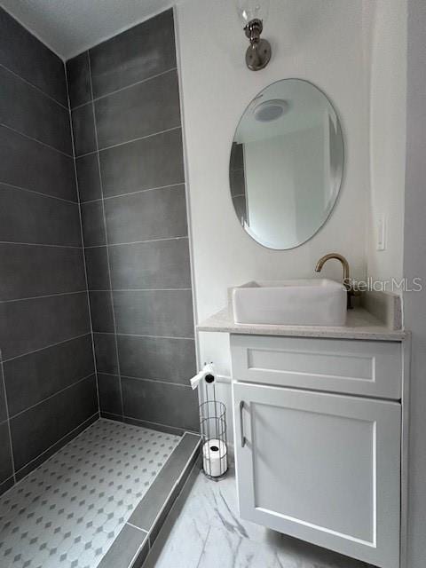 bathroom with marble finish floor, a stall shower, and vanity