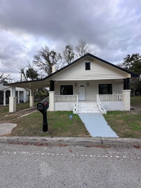 bungalow-style home featuring a carport, a porch, and a front yard