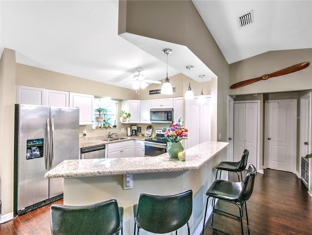 kitchen featuring lofted ceiling, appliances with stainless steel finishes, white cabinets, and decorative light fixtures