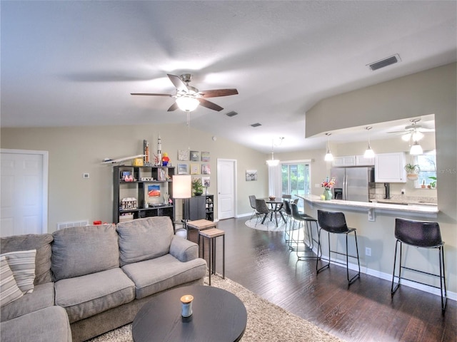 living room with dark hardwood / wood-style flooring, vaulted ceiling, and ceiling fan