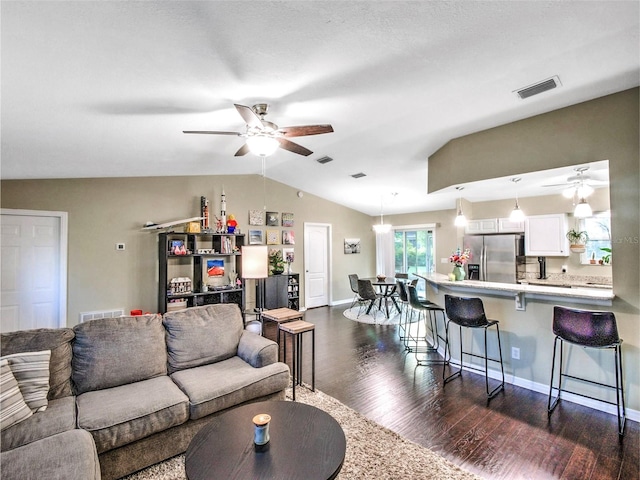 living room with ceiling fan, lofted ceiling, and dark hardwood / wood-style flooring