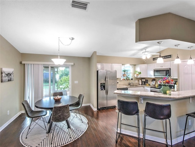 kitchen with appliances with stainless steel finishes, sink, white cabinets, dark hardwood / wood-style flooring, and hanging light fixtures