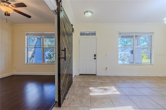 entryway featuring crown molding, a barn door, a wealth of natural light, and ceiling fan