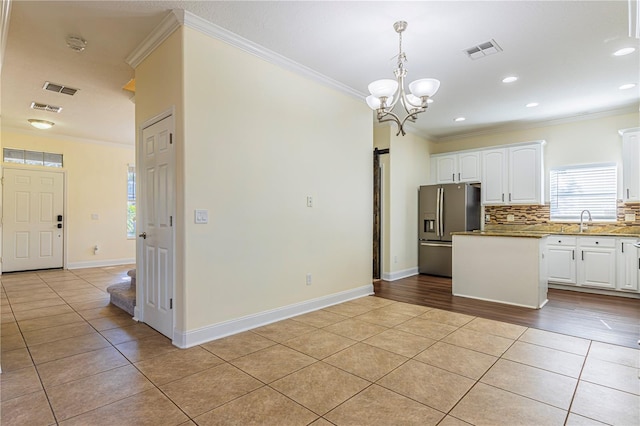 kitchen featuring white cabinetry, stainless steel fridge, ornamental molding, and light tile patterned flooring