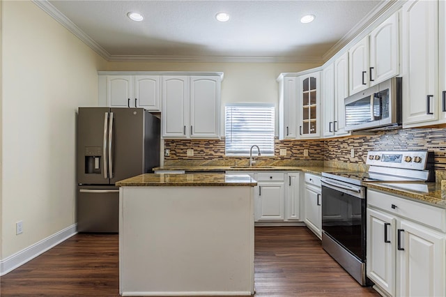 kitchen featuring appliances with stainless steel finishes, white cabinetry, dark hardwood / wood-style floors, a center island, and dark stone counters