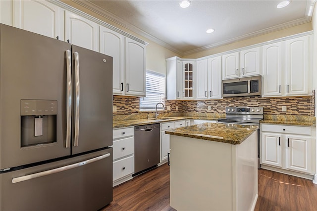 kitchen featuring a kitchen island, dark stone countertops, white cabinets, stainless steel appliances, and crown molding