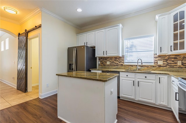 kitchen with stainless steel fridge, a barn door, and white cabinets