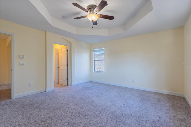 empty room featuring ceiling fan, carpet flooring, and a raised ceiling