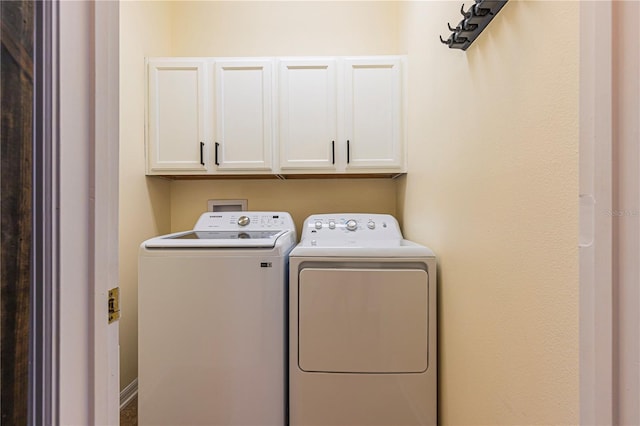 clothes washing area featuring cabinets and independent washer and dryer