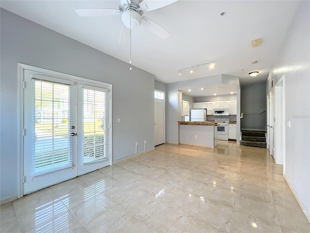 unfurnished living room with french doors, ceiling fan, rail lighting, and light tile patterned floors