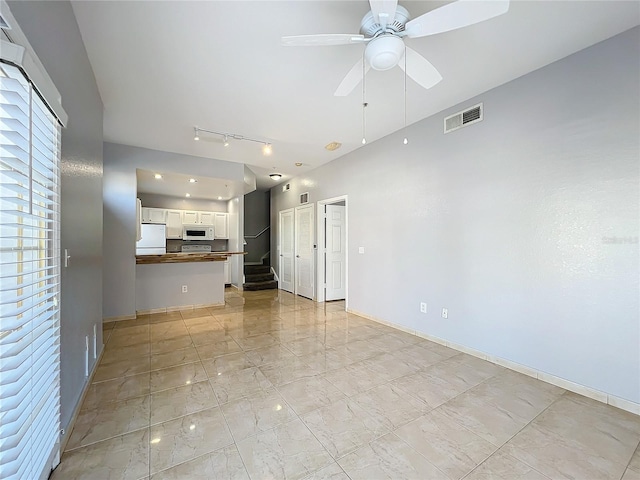 unfurnished living room with rail lighting and ceiling fan