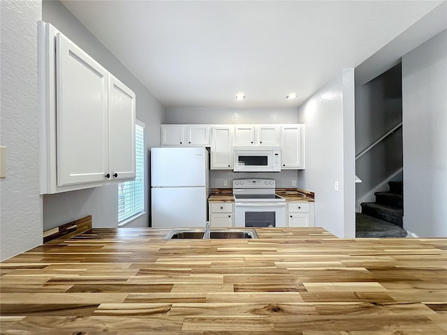 kitchen featuring white appliances, wooden counters, and white cabinets