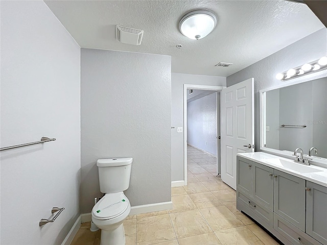 bathroom with vanity, toilet, and a textured ceiling