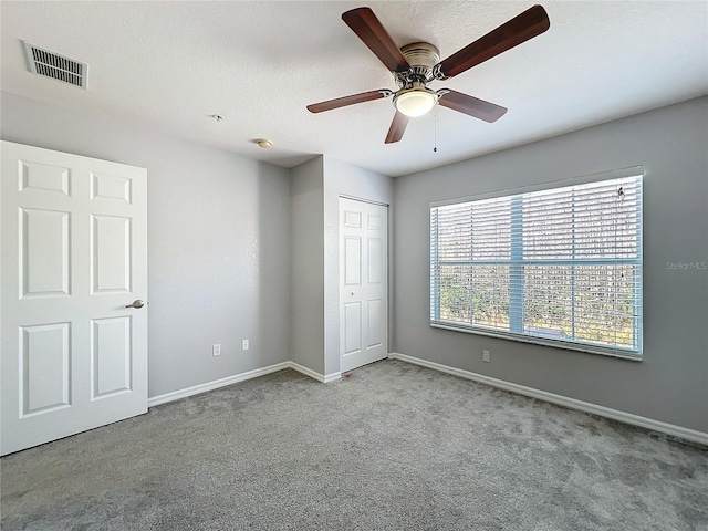 unfurnished bedroom with light carpet, a textured ceiling, a closet, and ceiling fan