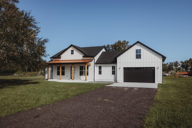 modern farmhouse featuring a garage, a porch, and a front lawn