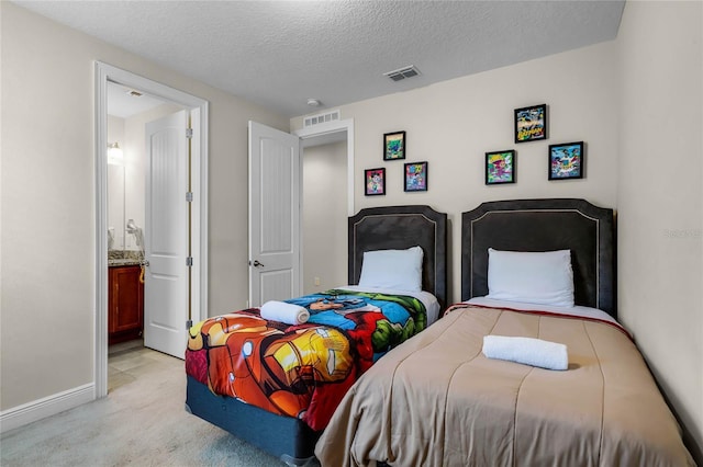 carpeted bedroom with ensuite bathroom and a textured ceiling