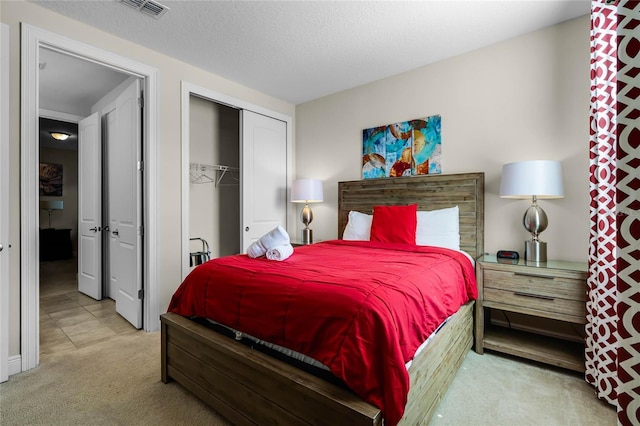 bedroom with light colored carpet, a textured ceiling, and a closet