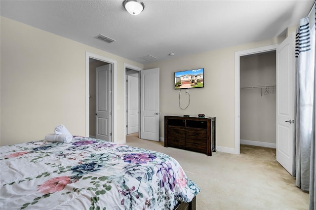 carpeted bedroom featuring a walk in closet, a closet, and a textured ceiling