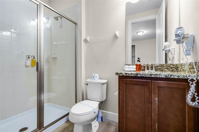 bathroom featuring tile patterned floors, vanity, toilet, and a shower with door