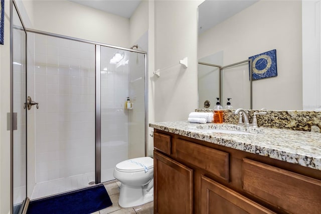 bathroom with tile patterned flooring, vanity, a shower with shower door, and toilet