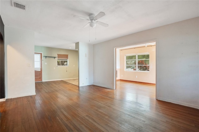 spare room featuring wood-type flooring, visible vents, ceiling fan, and baseboards