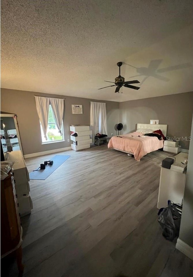 bedroom featuring ceiling fan, hardwood / wood-style floors, and a textured ceiling