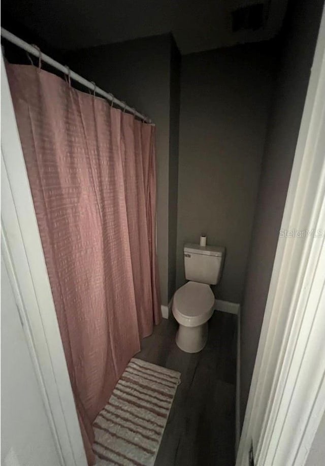 bathroom with walk in shower, hardwood / wood-style floors, and toilet