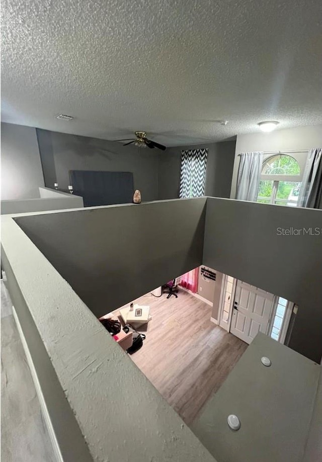 stairs with hardwood / wood-style flooring, ceiling fan, and a textured ceiling